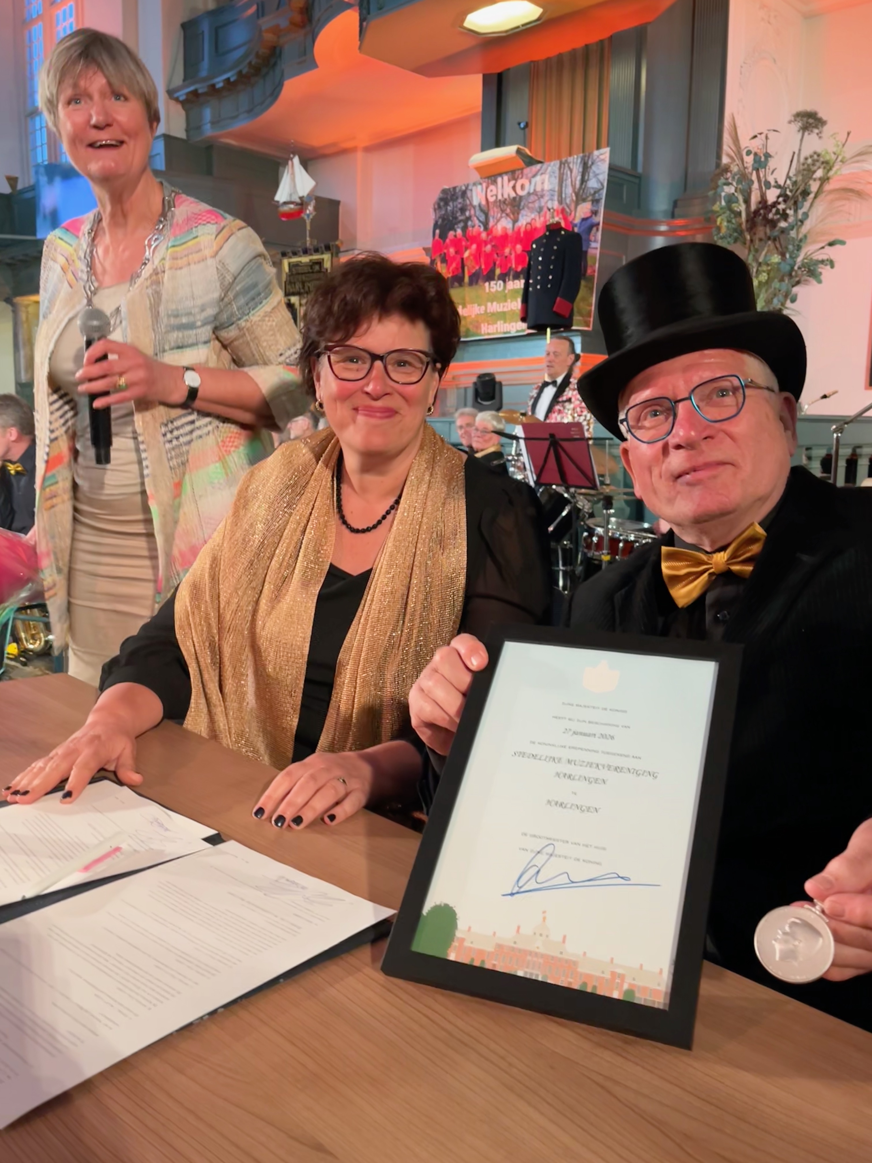 Burgemeester Ina Sjerps staand, secretaris Annemarie Zondervan en Vooriztter Gert Hegge na de ondertekening van stukken bij de erepenning